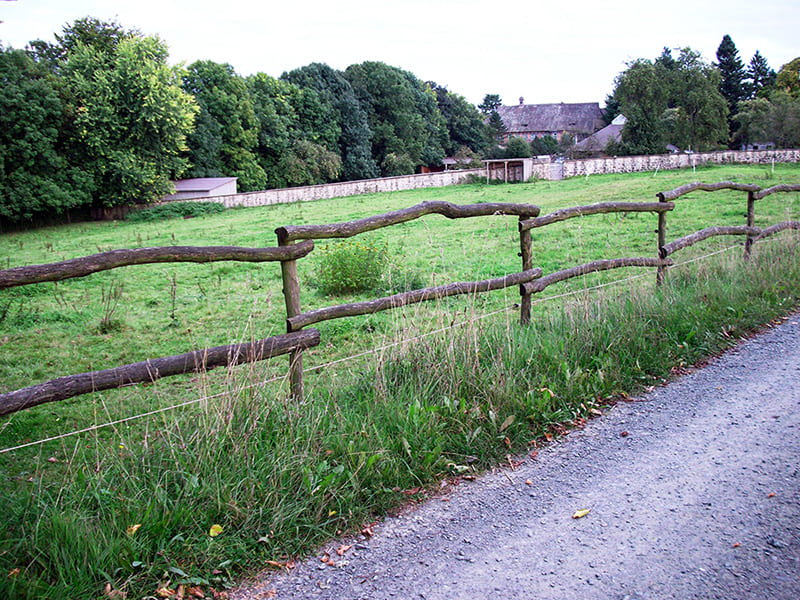 Ein Weidezaun aus Robinienholz direkt neben einem Kiesweg